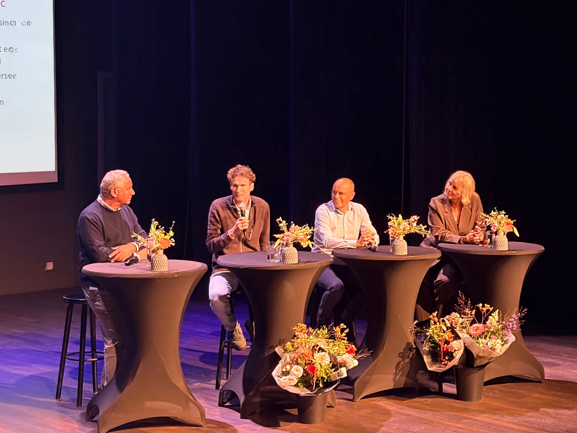 Paneldiscussie aan statafels met bloemen