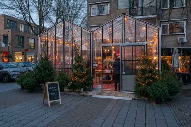 De kas in de avondschemering met kerstbomen en lichtjes